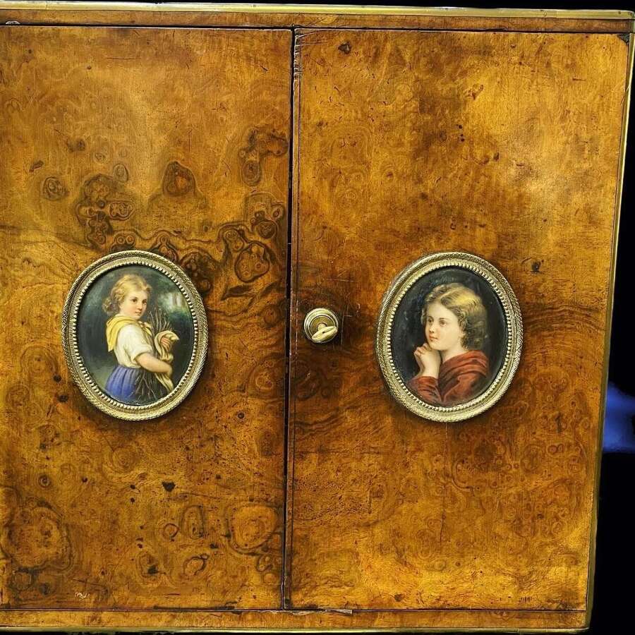A figured walnut table cabinet with miniature portraits, circa 1870.