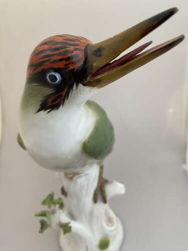 A Meissen porcelain model of a Green woodpecker perched on a tree stump.