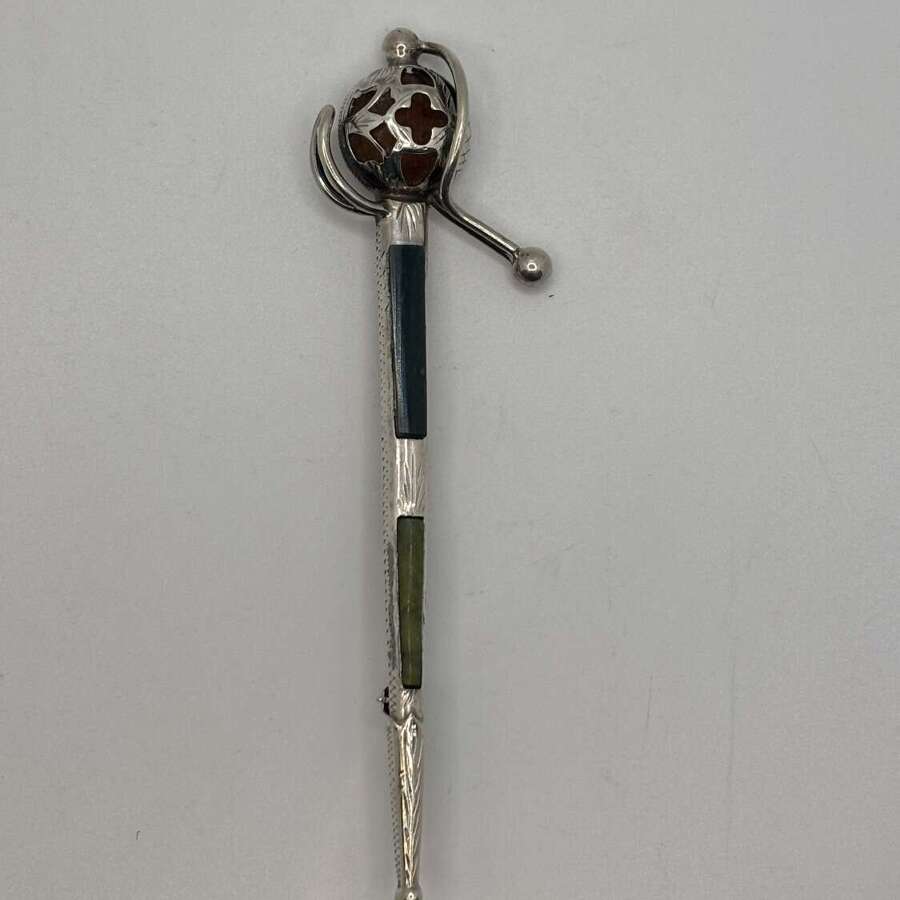 Silver kilt pin in the form of a basket hilted sword.