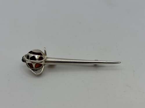 Silver pin in form of a basket hilted sword.
